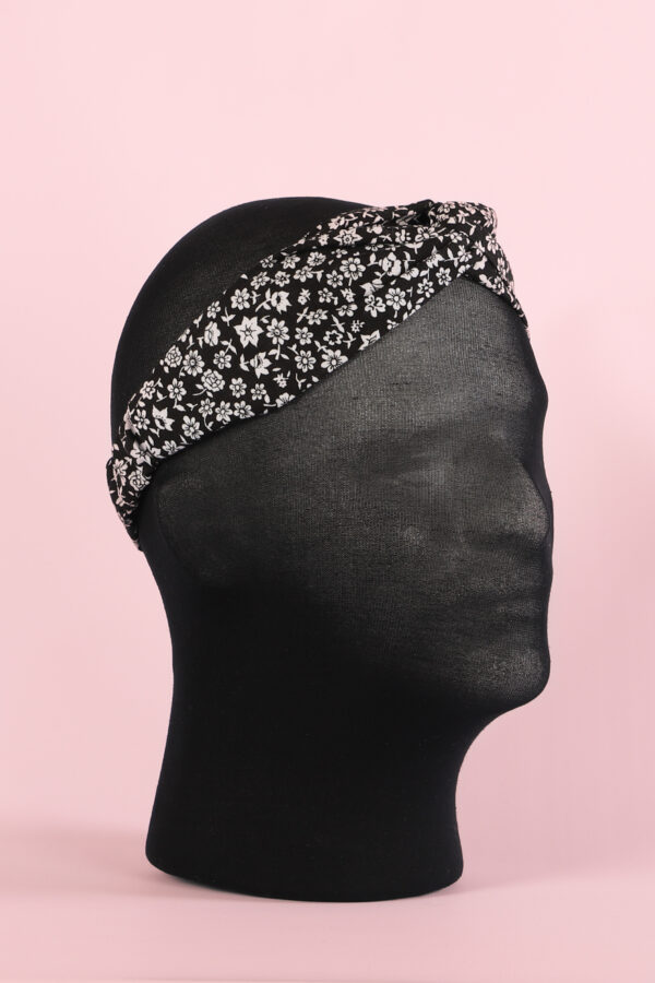 Haarband handgemaakt in zwart met witte bloemetjes patroon. Voor volwassene, kind, dames en meisje. Schuin van voren..